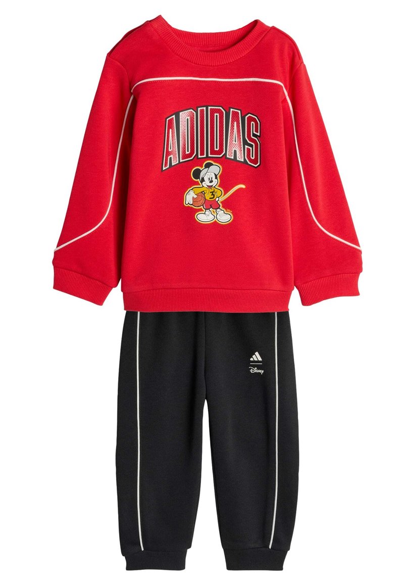 Crvena majica dugih rukava s natpisom "ADIDAS" i grafikom Mickey Mousea, u kombinaciji s crnim hlačama opremljenim bijelim detaljima i Adidas logom.