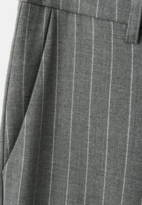 Pantalon en tissu gris avec de fines rayures verticales blanches et une poche latérale visible près de la ceinture et de la passants de ceinture.