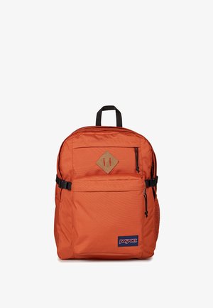 Orange Jansport rygsæk med sort håndtag, forreste lynlåslomme, sidelomme i net og brun diamantformet patch på ens hvid baggrund.