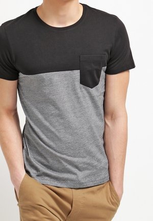Sort og grå kortærmet T-shirt med en brystlomme; lavet af blødt stof; har et farveblokdesign og en glat tekstur.
