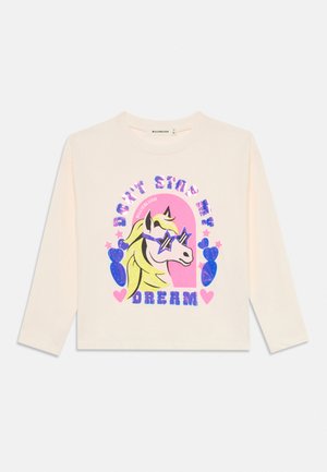 Camicia crema a maniche lunghe con grafica colorata di un cavallo che indossa occhiali da sole a forma di stella e testo "Don't Stop Dream" circondato da cuori e forme.