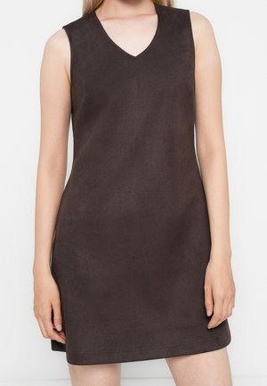Robe sans manches marron foncé à texture suédée avec décolleté en V, portée par une personne avec les mains reposant sur les côtés, sur un fond blanc uni.