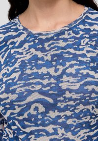 Blå och vit mönstrad stickad topp med rund halsringning, med en djärv abstrakt design och en mjuk, lätt textur.