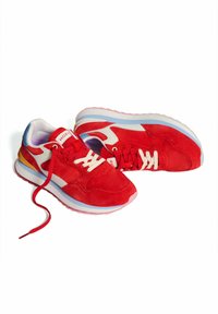 Zapatillas deportivas de ante rojo con detalles en blanco, suelas azul y rosa, y cordones blancos. Presentan un diseño curvado y un logotipo en la lengüeta.