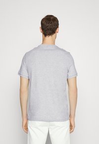 Camiseta gris de manga corta en suave mezcla de algodón, cuello redondo, corte relajado, costuras visibles en puños y dobladillo. Sin estampados ni gráficos.