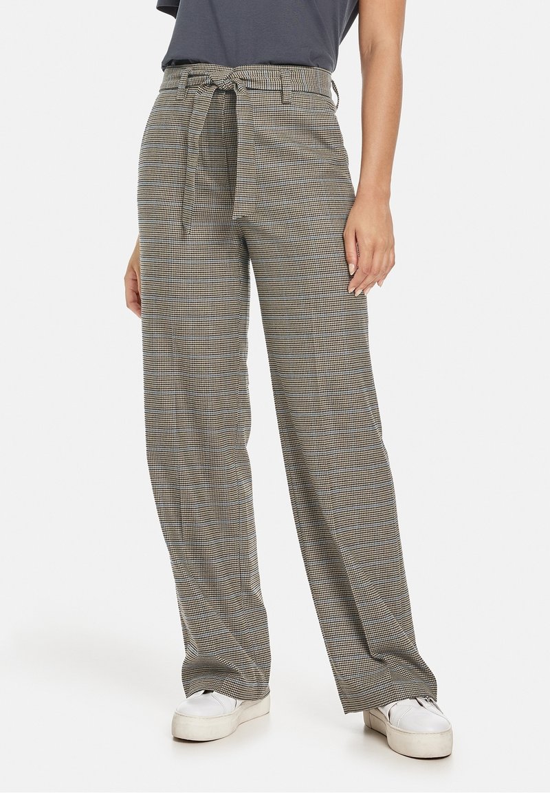 Pantalons à jambes larges en tartan gris et blanc, dotés d'une taille à nouer et d'une texture de tissu douce. Associés à des baskets blanches pour un contraste.