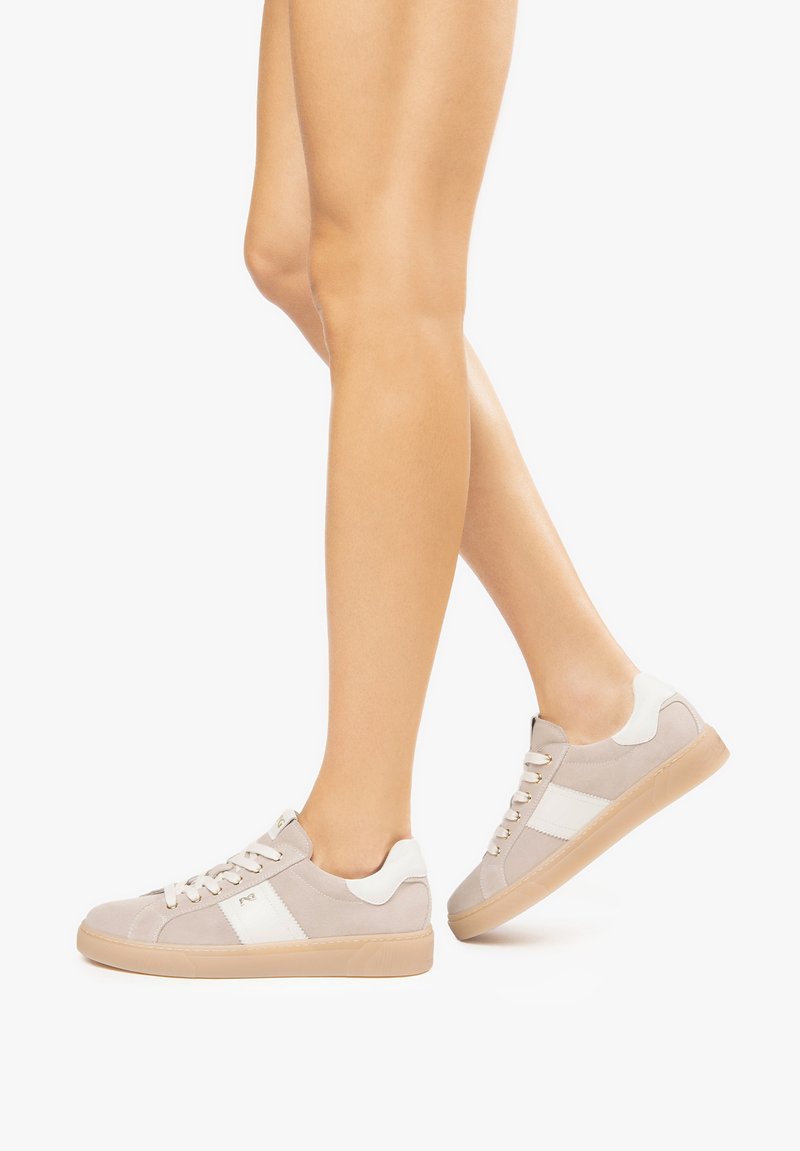 Beige sneakers with white accents, textured suede material, round toe, flat rubber sole, and lace-up closure.