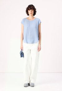 Gai zila īsām piedurknēm blouse, baltas platajām biksēm, pelēkas kurpes un neliela zila clutch soma. Vienkārša, gluda tekstūra, brīvs piegriezums.