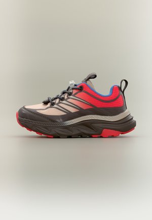 Trailrunning-Schuh mit roten, beigen und schwarzen Akzenten, blauem Innenfutter und dicker, strukturierter Sohle, von der Seite auf neutralem Hintergrund betrachtet.