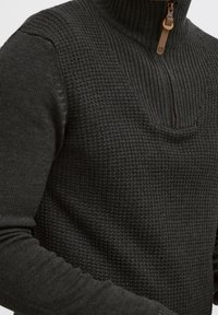 Dark gray knit sweater featuring a high collar with a half-zip closure, textured pattern, and ribbed sleeve cuffs for added warmth.