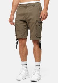 Shorts cargo en coton de couleur vert olive, avec des poches latérales, des cordons de réglage à l'ourlet et une fermeture à bouton sur le devant.