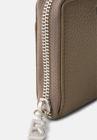 Cartera de cuero texturizada marrón con un cierre de plata, que presenta un broche decorativo de plata con un acento de "B". El cierre se extiende a lo largo de un borde.