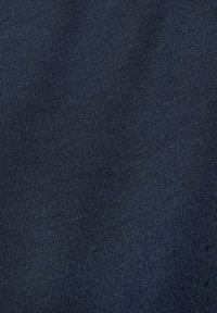 Gros plan d'un tissu tricoté bleu foncé montrant une texture textile fine, tissée serrée avec des côtes verticales subtiles.