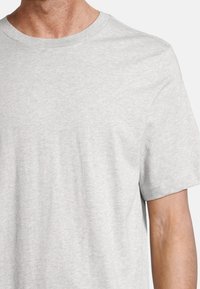 T-shirt en coton gris clair avec des manches courtes et un col rond classique. Texture lisse avec un motif chiné subtil. Design simple.