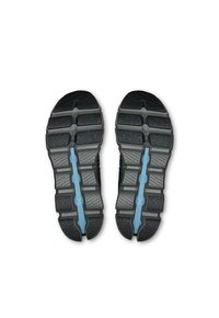 Chaussures de sport avec des semelles en caoutchouc noir texturé, présentant une bande centrale bleue, des rainures profondes et un design segmenté pour une meilleure traction.
