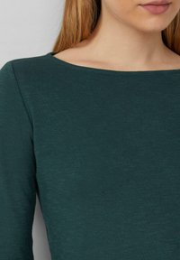 Dark green long-sleeve top with a wide neckline, made of textured fabric, featuring a close-fitting design and seamless stitching details.