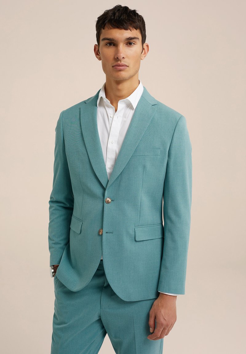 Chaqueta de traje turquesa con un acabado texturizado, cierre de un botón, solapas en pico y bolsillos con solapa, combinada con una camisa blanca.