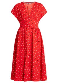 Vestido floral rojo con mangas cortas, escote en V profundo, cintura elástica y una falda fluida con pequeños patrones de flores blancas y negras.