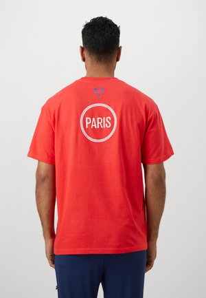 Rød bomulds t-shirt med et cirkulært hvidt grafisk motiv med teksten "PARIS" på ryggen og en blå logo detalje ved udskæringen.