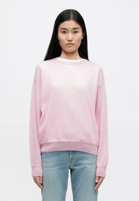 Pulover roz deschis cu guler rotund, cu o textură moale și mansete cu nervuri, combinat cu blugi bleu deschis, având un design casual, lejer.