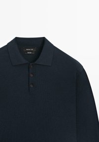 Donker marineblauw poloshirt met lange mouwen, voorzien van drie bruine knopen en een spreadkraag, gemaakt van 100% katoen.