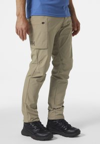 Beige cargobroek met ritssluitingen en een logo-patch. Gemaakt van lichte stof, met een slim fit en versterkte naden.