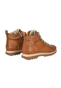 Botas de cuero marrón hasta el tobillo con un acabado texturizado, que presentan cordones metálicos, costuras en contraste y una suela de goma con un diseño dentado.