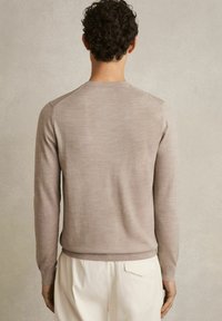 Lichtbeige gebreide trui met lange mouwen en een ronde halslijn. Beschikt over geribde manchetten en onderrand, een gladde textuur en een aansluitend ontwerp.