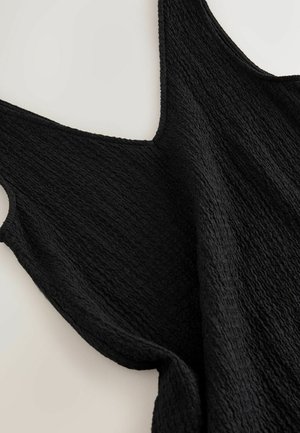 Juodas tekstūruotas viršus su laisvu kirpimu, turintis platų iškirpimą ir storas petnešas, rodantis bangų raštą per audinio paviršių.