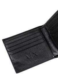 Portafoglio in pelle nera con sei slot per carte, texture liscia, logo impresso "A|X" e design minimalista. Vista aperta che mostra la disposizione interna.