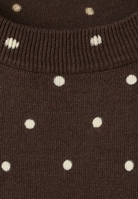 Tissu marron tricoté avec des pois blancs et un détail de col côtelé.