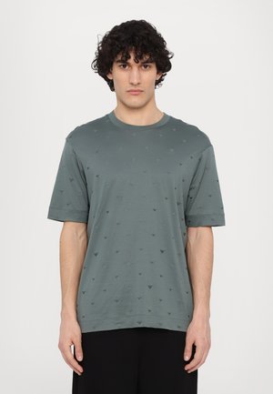 Short-sleeve crewneck t-shirt in muted green cotton, featuring a subtle pattern of small gray triangular shapes throughout the fabric.