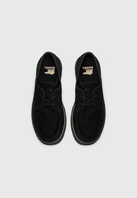 Scarpe in suede nere con un design classico, dotate di lacci, punta arrotondata, cuciture bianche lungo la suola e un logo sulla soletta.
