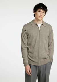 Bežna zip-up jopica s ovratnikom, izdelana iz mehkega blaga. Ima polno dolžino rokavov in rebraste manšete. Ujemite jo s sivo hlačami.