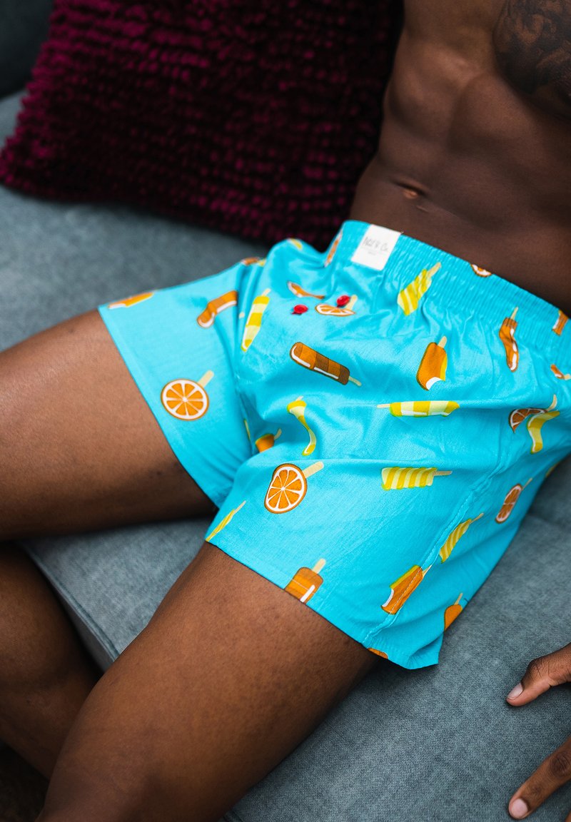 Tyrkysové boxerky s potiskem pomerančových plátků a zmrzlinových kornoutů. Vyrobené z lehkého materiálu s elastickým pasem.