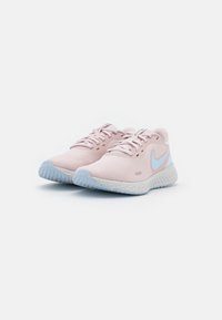 Baskets de sport rose clair avec une tige en maille respirante, dotées de subtils accents bleus et d'une semelle blanche texturée pour une meilleure adhérence.