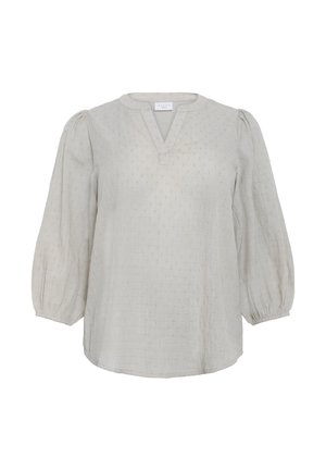 Helle beige Bluse mit V-Ausschnitt, dreiviertel Puffärmeln, strukturiertem Stoff und kleinen Punkten über die Oberfläche verteilt.