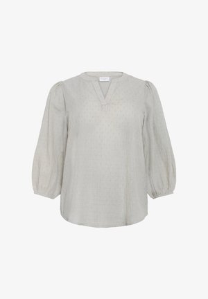 Ljusbeige blus med V-ringning, trekvarts puffärmar, textilerad stoff och små prickar över ytan.