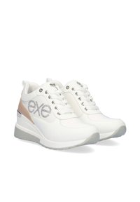 Zapatillas blancas con parte superior de cuero liso, ojales plateados y detalles con logo. Presentan un acento beige en el talón y una suela gris.