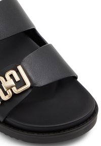 Black slide sandal featuring two wide straps and a gold-tone decorative buckle. Smooth material with a cushioned sole and rounded toe design.