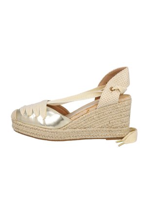 Sandalia de cuña estilo espadril con suela de yute trenzada, puntera metálica dorada, envoltura de tela color crema en el tobillo y soporte de talón a cuadros.