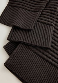 Mørkebrun sweater med ribbet tekstur og manchet-detaljer, der fremviser et lagdelt design med folder og kontrasterende strikkemønstre.