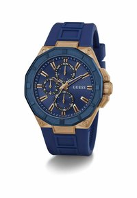 Reloj con correa de silicona azul y caja octagonal en azul y tono dorado. Presenta tres subdiales, indicador de fecha y marcadores de hora dorados.