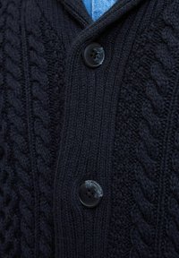 Marine gebreide cardigan met een kabelpatroon, voorzien van een sjawlboord en twee zwarte knopen aan de voorkant. Zachte textuur.