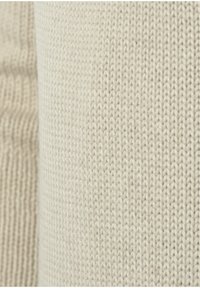 Lichtbeige gebreide stof met een gestructureerd patroon. Het materiaal lijkt zacht en heeft een uniform ontwerp met zichtbare stiksels.