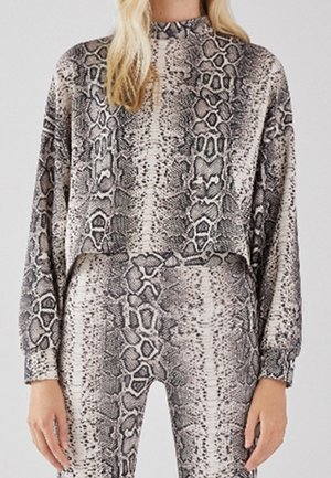 Forkortet pullover og matchende leggins i et slange mønster. Materialet ser blødt ud med en glat tekstur i nuancer af grå og creme.