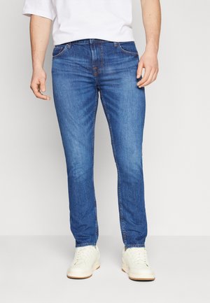 Blauwe denim jeans met een rechte snit, voorzien van een klassieke vijf-pocketontwerp en subtiele vervaging, gedragen met witte sneakers.