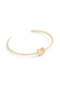Pulsera de brazalete de oro con un detalle de mariposa que presenta alas texturizadas y un pequeño acento de gema en el centro. Acabado de metal suave y pulido.