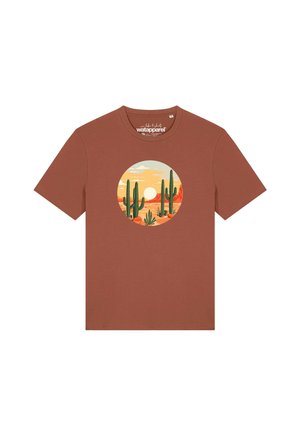 T-shirt marron à manches courtes avec un motif circulaire représentant un paysage désertique avec des cactus verts, des formations rocheuses orangées et un soleil couchant.