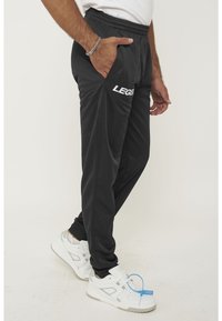 Zwarte sportbroek met een elastische tailleband, zijzakken en het logo "LEGEND". Heeft een slank ontwerp en een lichte textuur.